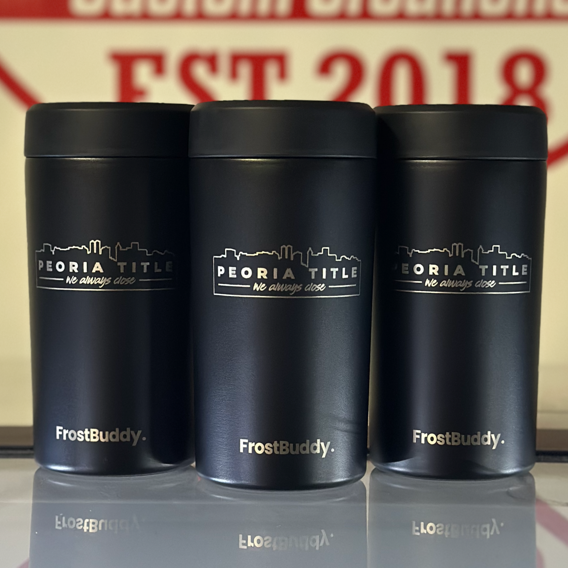 Three black FrostBuddy Universal Can Coolers with the 'Peoria Title' logo printed on them.