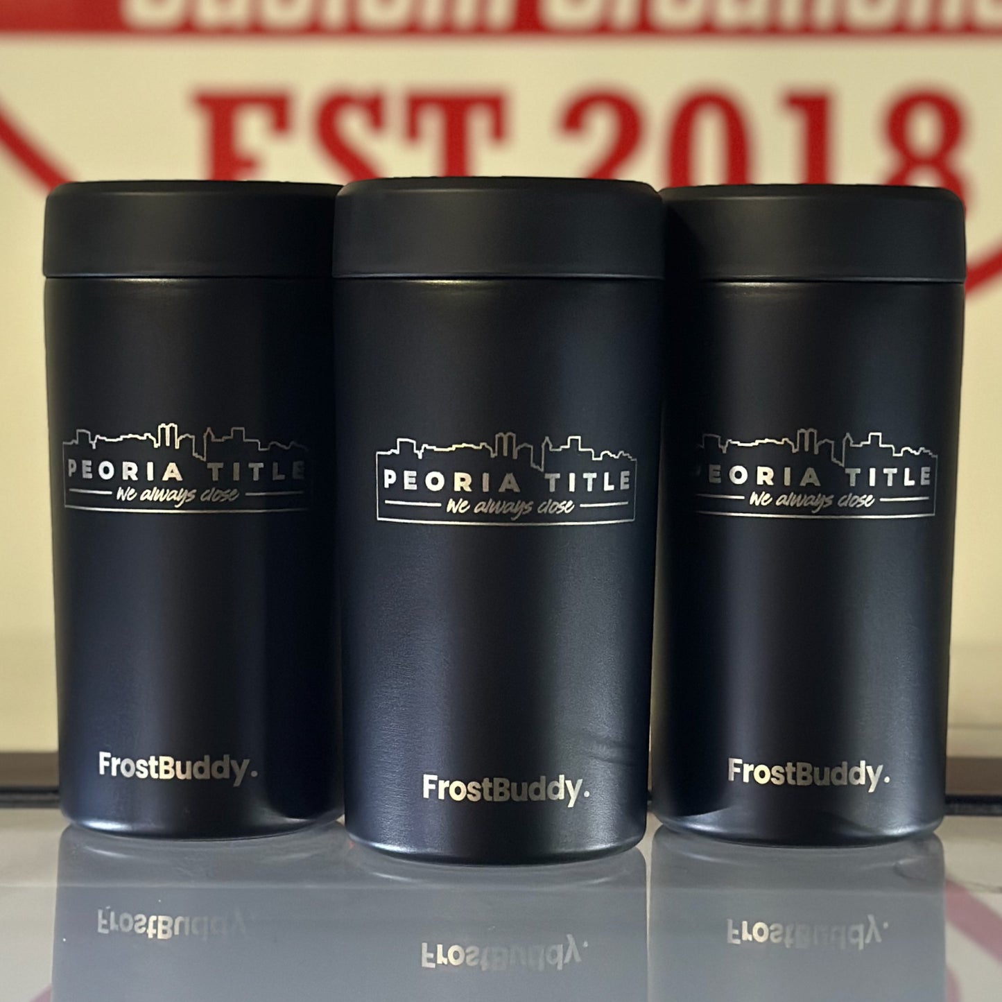 Three black Station 2 Custom Creations FrostBuddy Universal 2.0 can coolers with custom Peoria Title laser engraving.